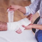 Injury leg. Young man with injured leg. Young woman doctor helps the patient