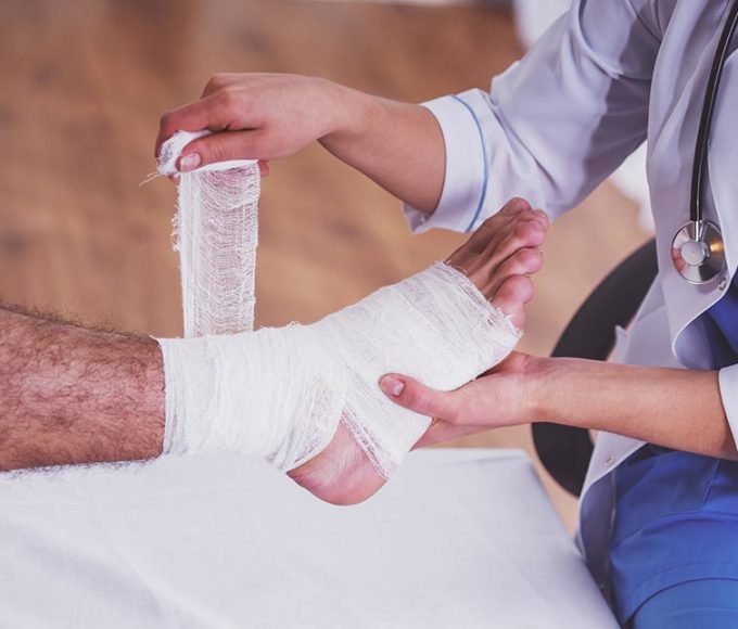 Injury leg. Young man with injured leg. Young woman doctor helps the patient