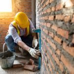 Man bricklayer installing bricks on construction site