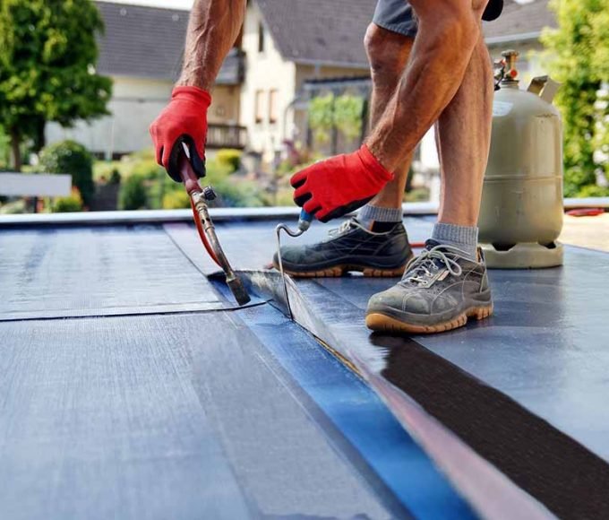 Flat roof installation with propane blowtorch during constructio